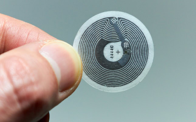 Person holding up a NFC tag, image shows exposed coil.