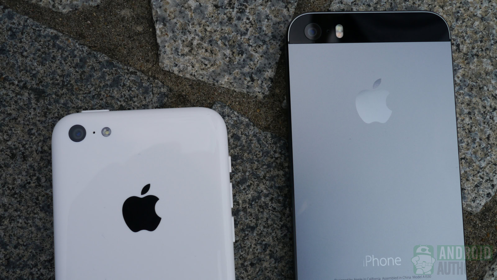 An iPhone 5C lying face-down on pavers next an iPhone 5S lying face-down.