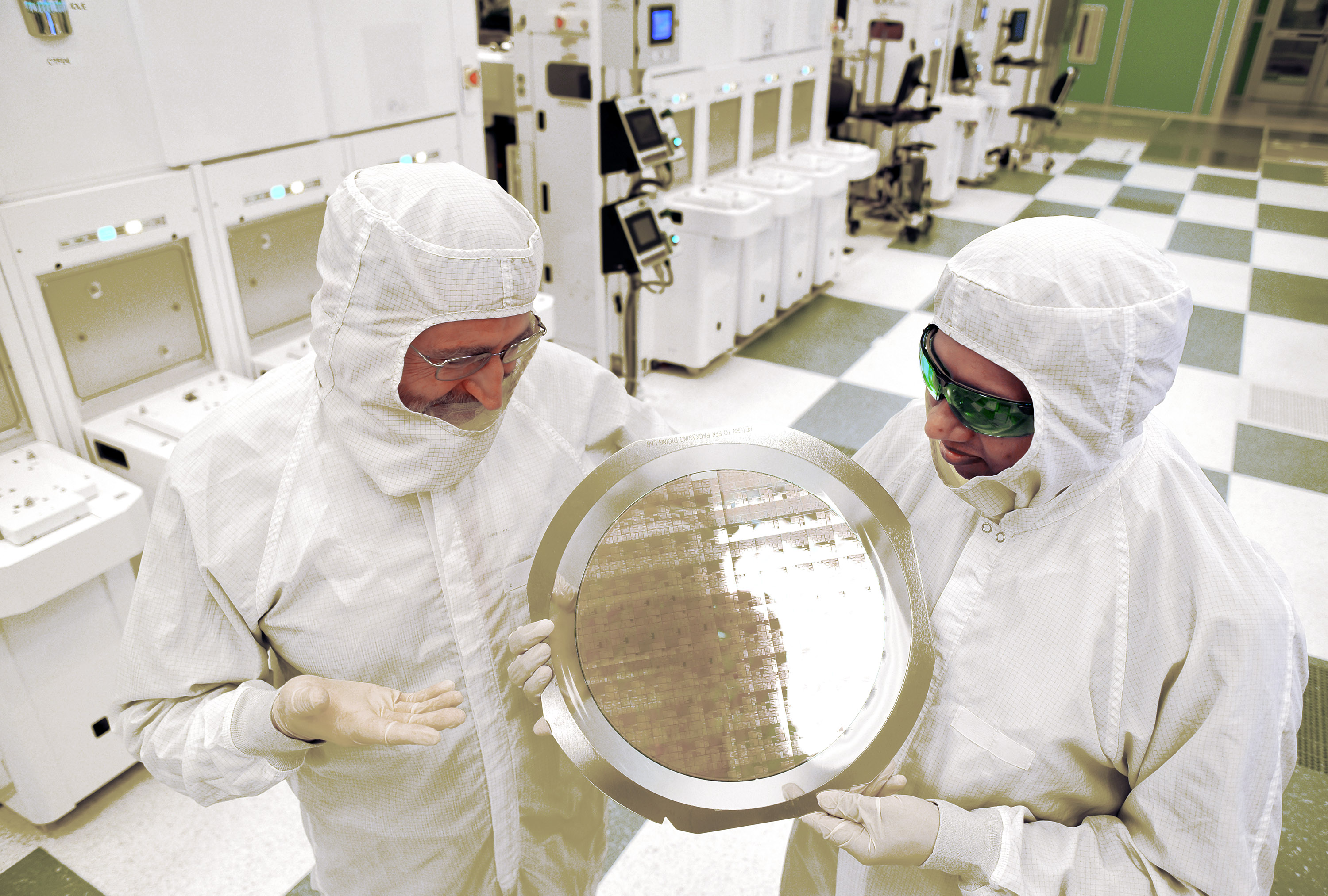 SUNY College of Nanoscale Science and Engineering's Michael Liehr, left, and IBM's Bala Haranand look at wafer comprised of 7nm chips on Thursday, July 2, 2015, in a NFX clean room Albany. Several 7nm chips at SUNY Poly CNSE on Thursday in Albany. (Darryl Bautista/Feature Photo Service for IBM)