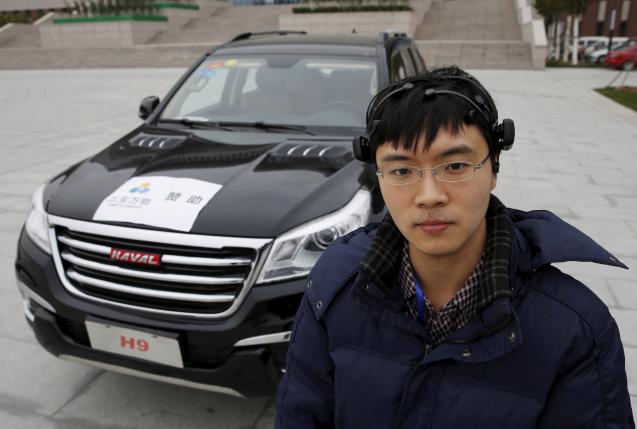 Researcher Zhang Zhao wearing a brain signal-reading equipment poses with a vehicle which can be controlled with his brain wave, during a demonstration at Nankai University in Tianjin, China, November 17, 2015.        REUTERS/Kim Kyung