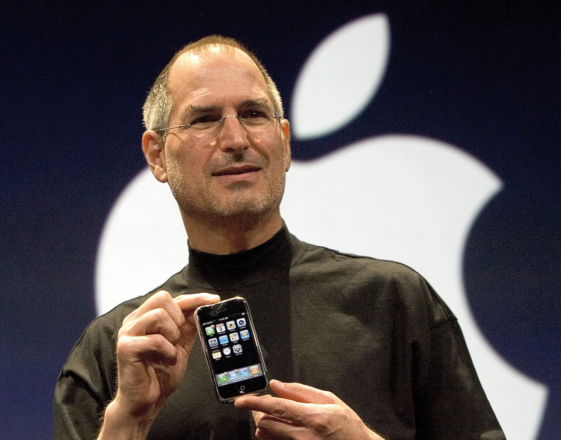 Steve Jobs holding the original iPhone.