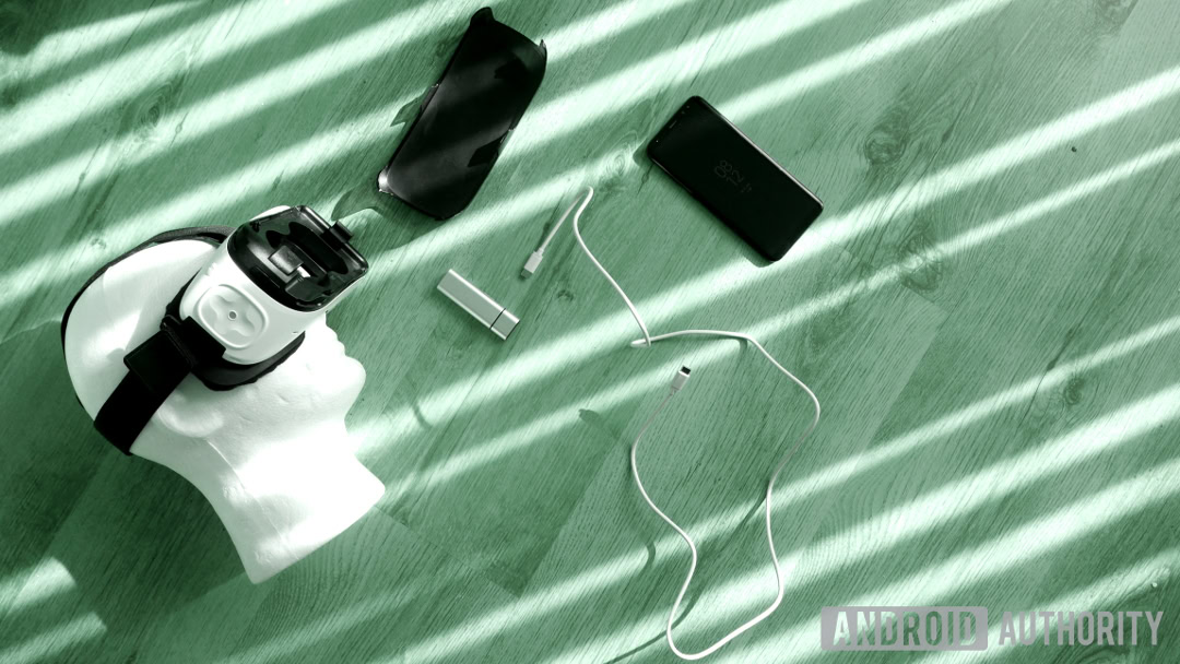 Top view of a Samsung gear virtual reality kit with Galaxy S8 laid on a wooden floor.