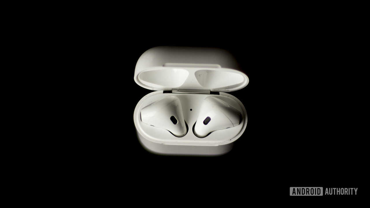The first-generation Apple AirPods in the case on a black background.