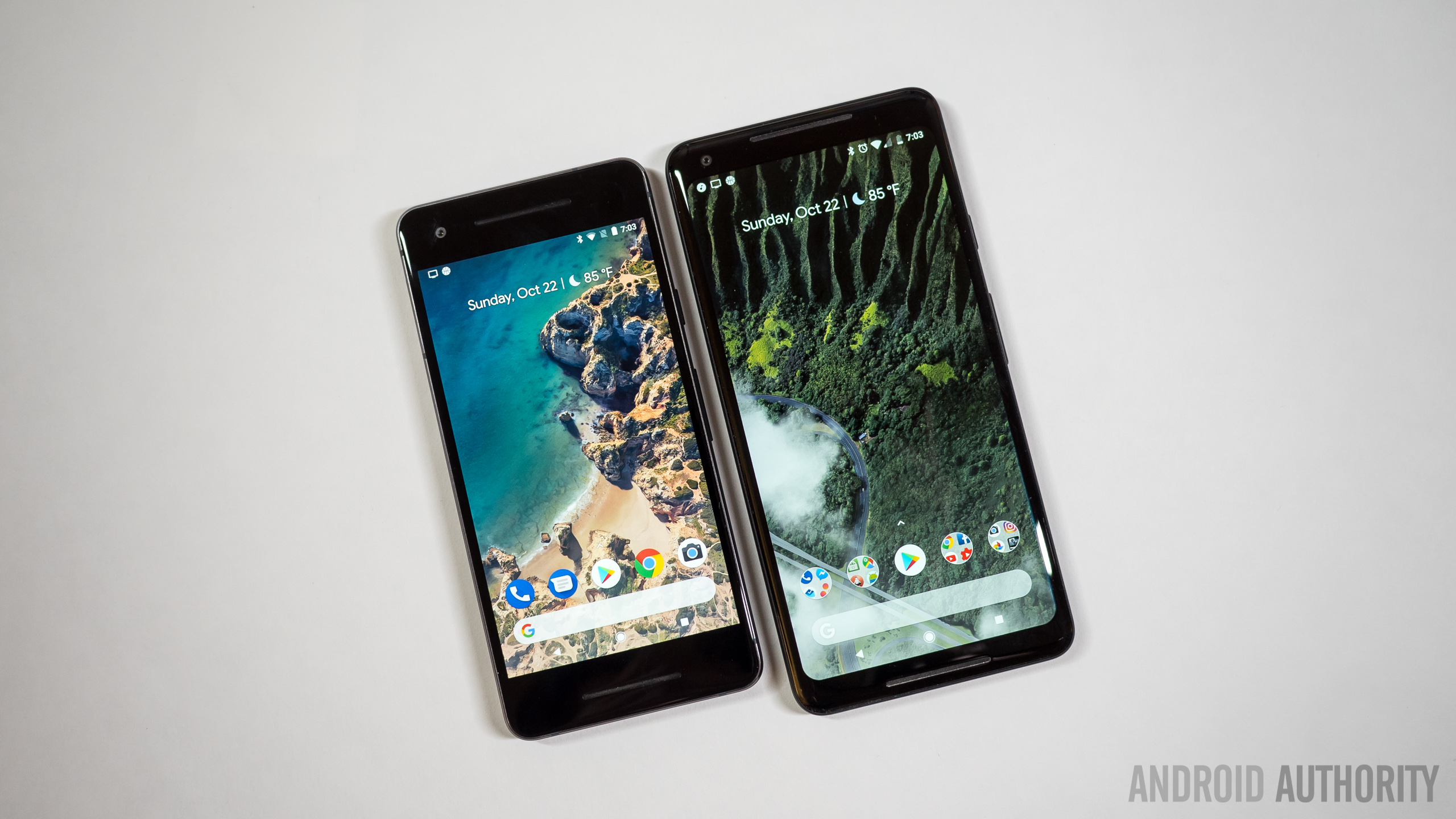 The Google Pixel 2 and the Google Pixel 2 XL, side-by-side, face-up on a white desk.