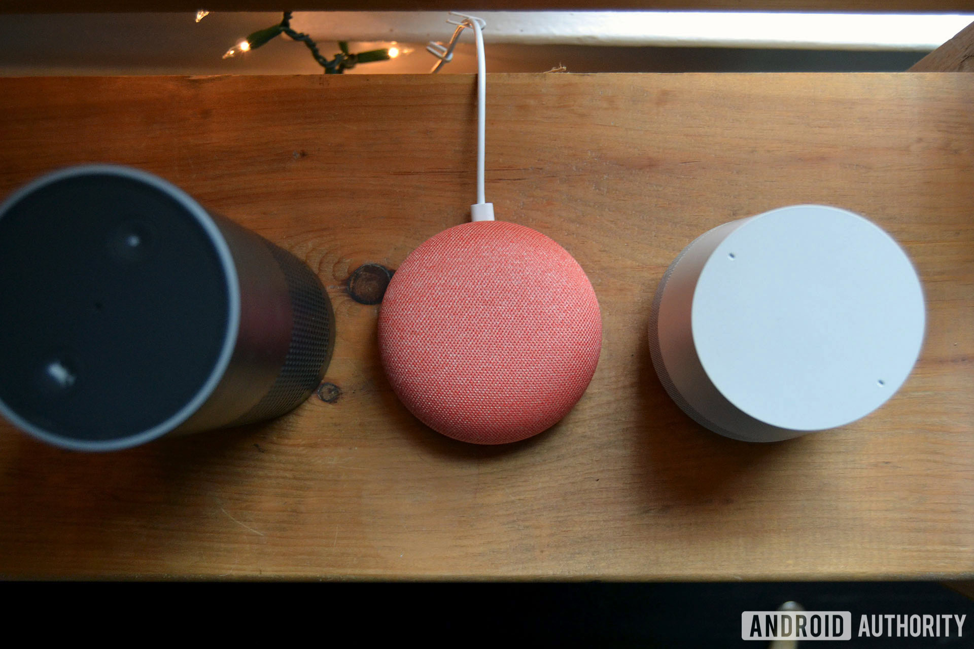 Amazon Echo, Google Home Mini, and Google Home top-down image on wood table.