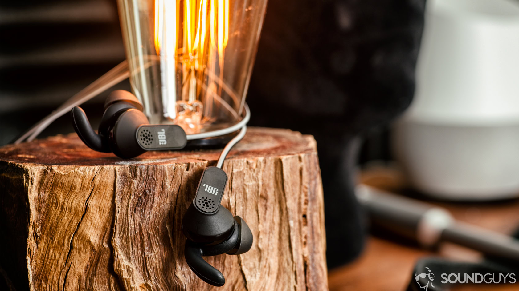 USB-C audio JBL Reflect Aware on a piece of wood with an Edison light bulb sticking out from it.