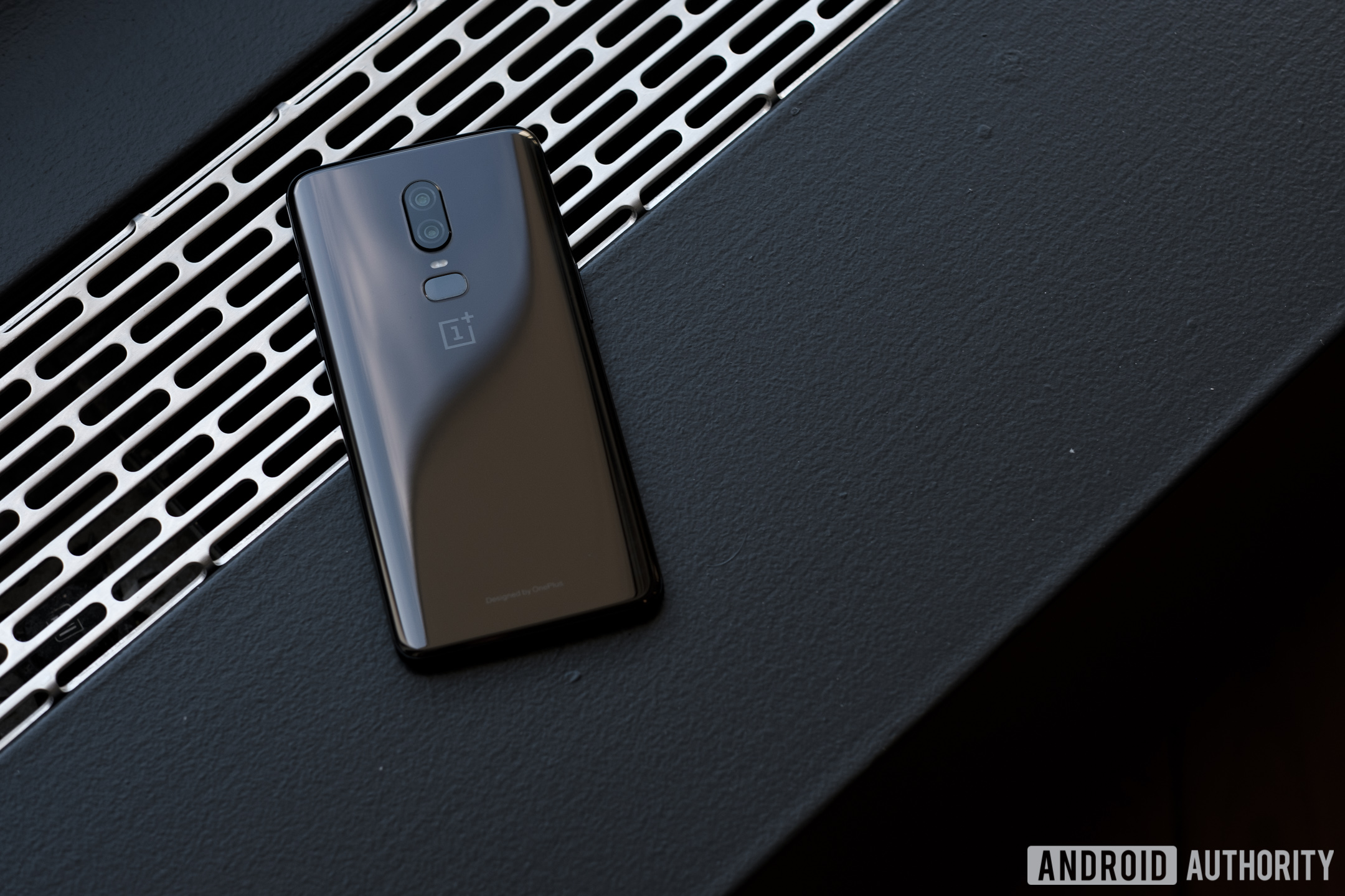 The OnePlus 6 smartphone in black lying face-down against metal.