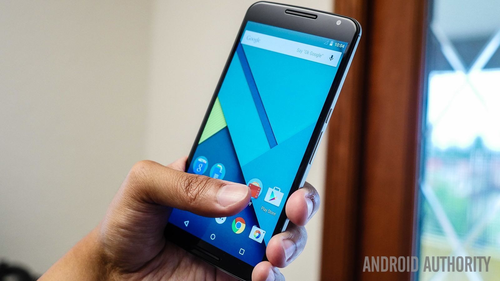 A Nexus 6 smartphone in a person's hand with blue wallpaper.
