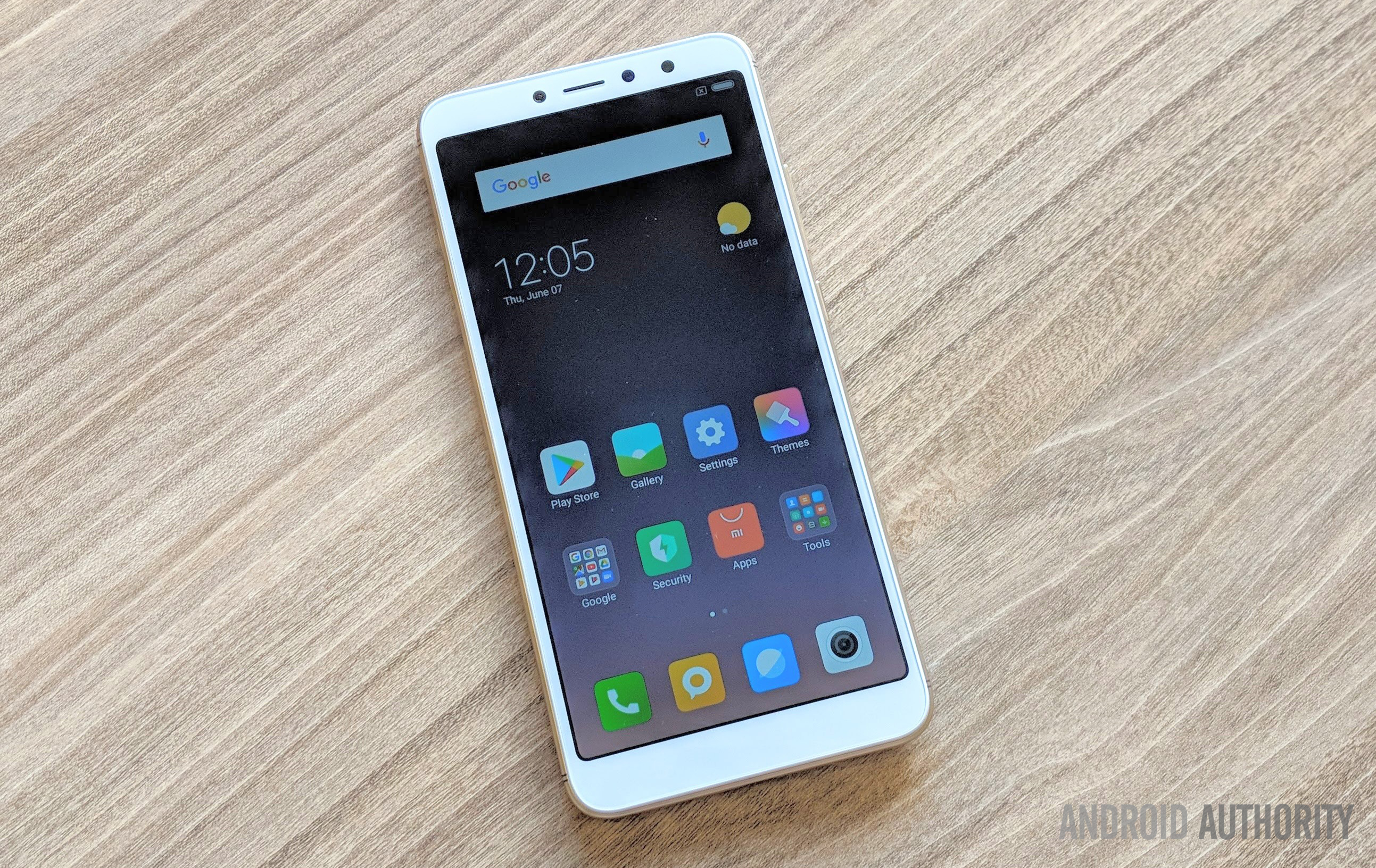 Xiaomi Redim Y2 smartphone in white, face-up on a wooden desk.