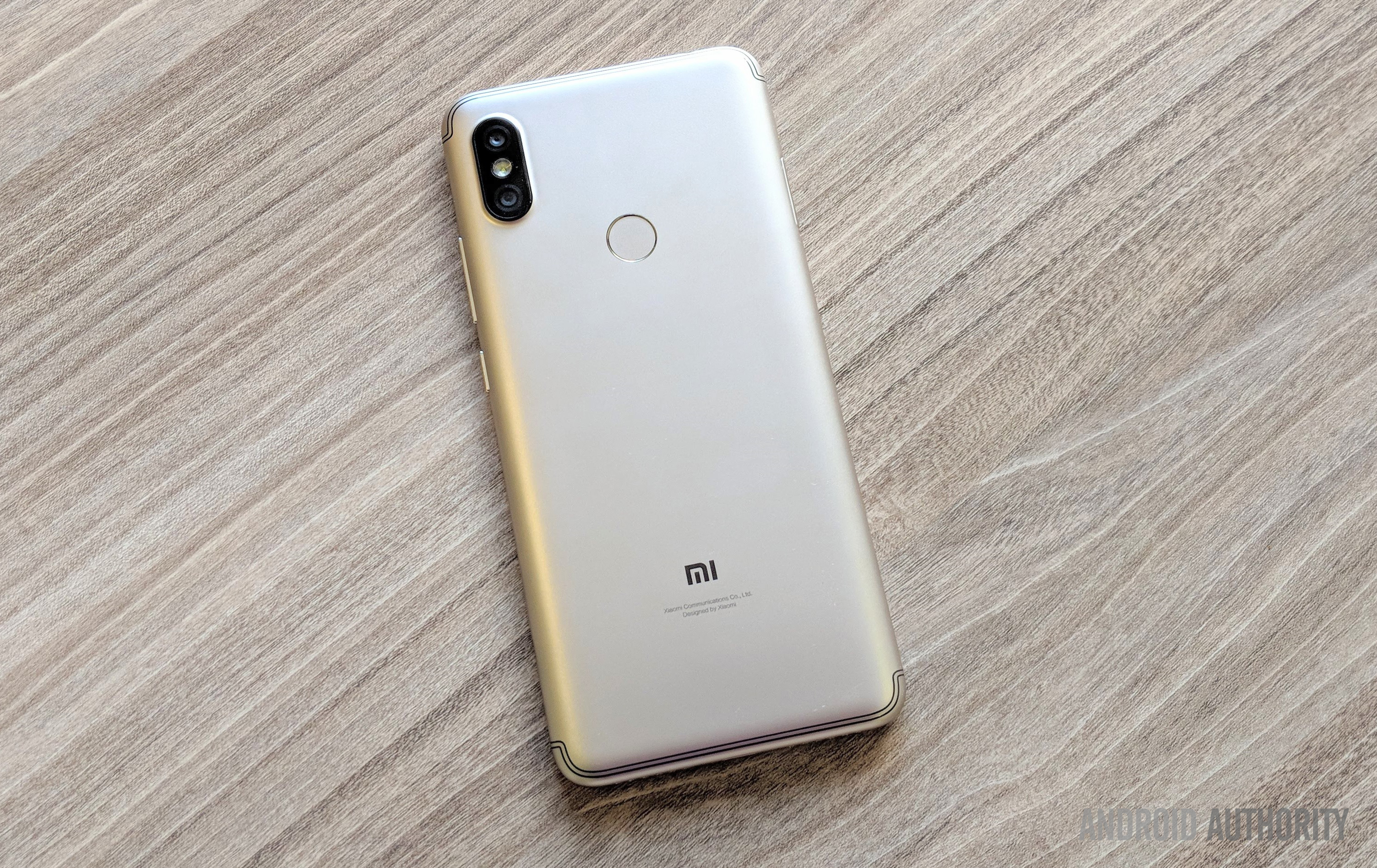 Xiaomi Redim Y2 smartphone with a gold back, face-down on a wooden desk.