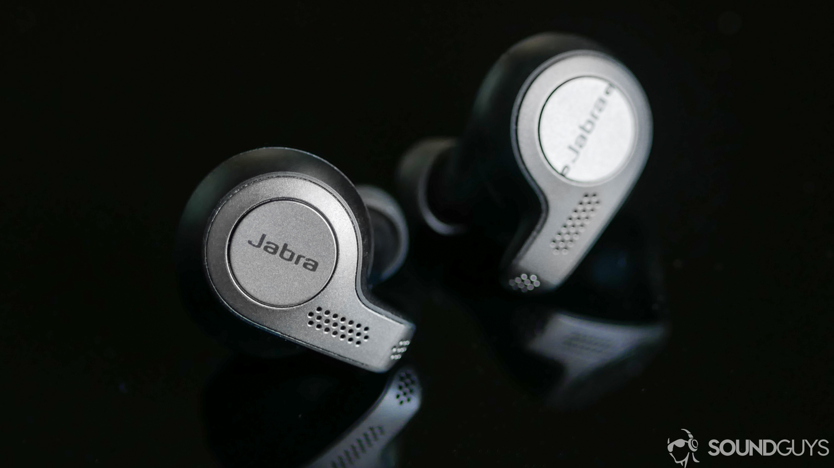 A photo of the Jabra Elite 65t true wireless earbuds on black reflective surface.