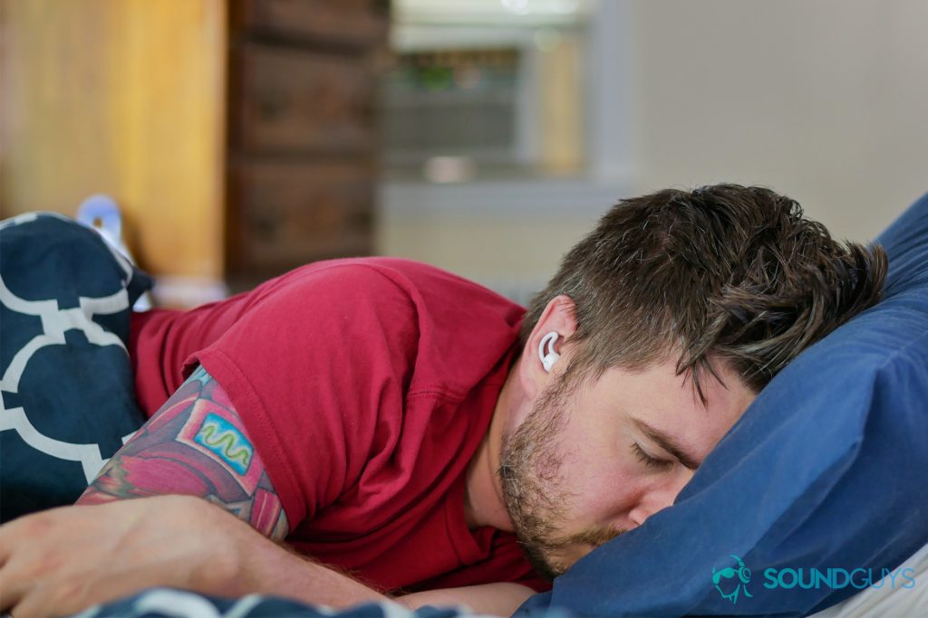 A photo of Chris sleeping in a bed, while using the Bose Sleepbuds near an air conditioner.