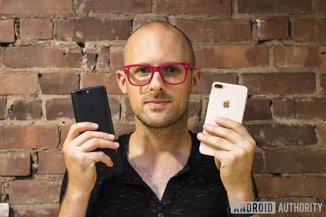 C. Scott Brown from Android Authority holding a OnePlus 5 in his right hand and an iPhone 8 Plus in his left hand.