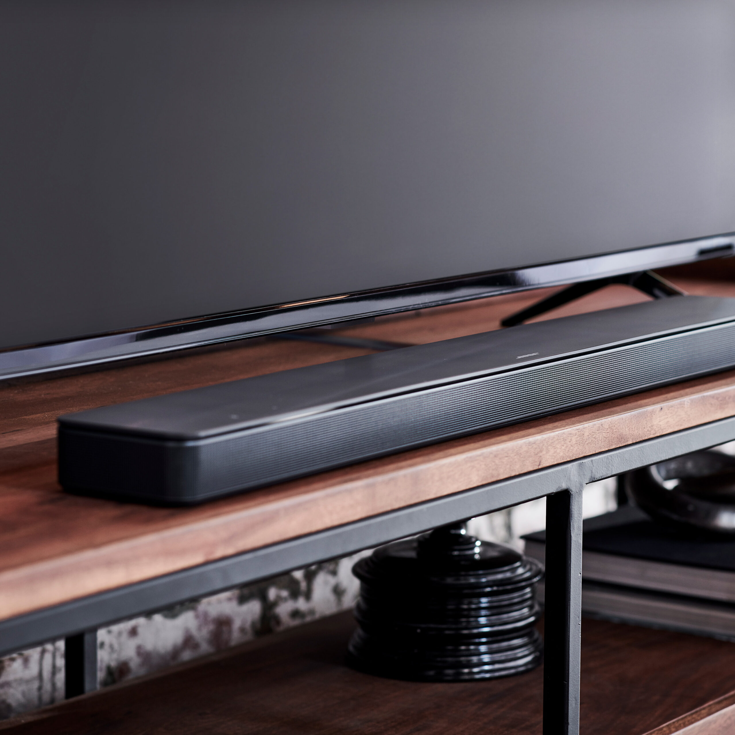 Bose smart speaker soundbars: Product image of the Bose Souundbar 500 from Bose press release. The soundbar sits ona wood TV stand with a TV above it.