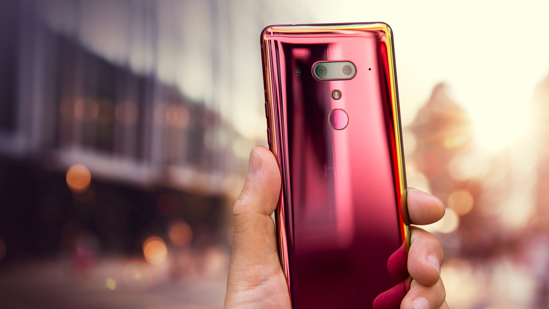 An Image of a hand holding a HTCU12 Plus Flame Red edition.