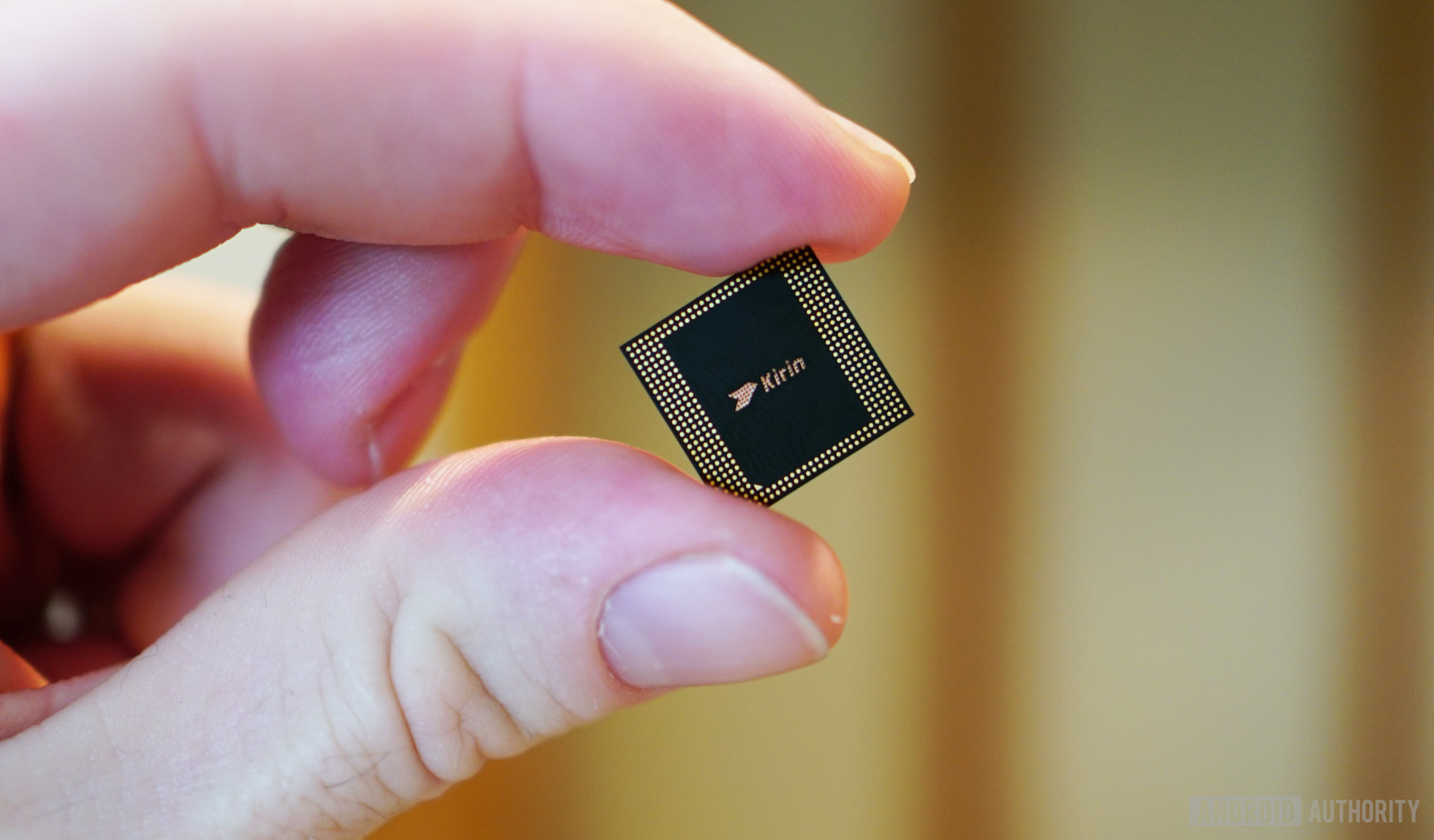 The HUAWEI Kirin 980 chipset between a person's finger and thumb.