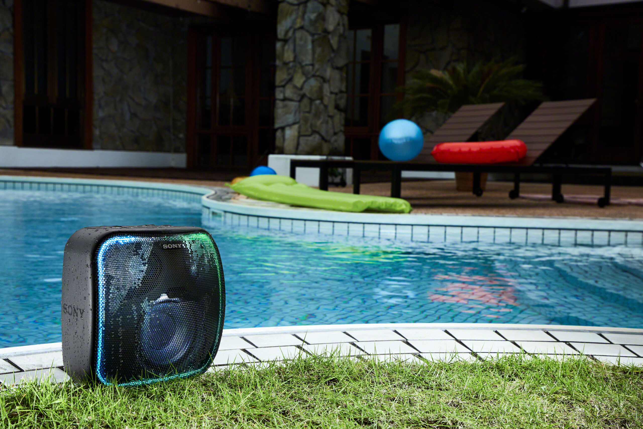 Sony SRS-XB501G press release image of the speaker on the grass by a pool.