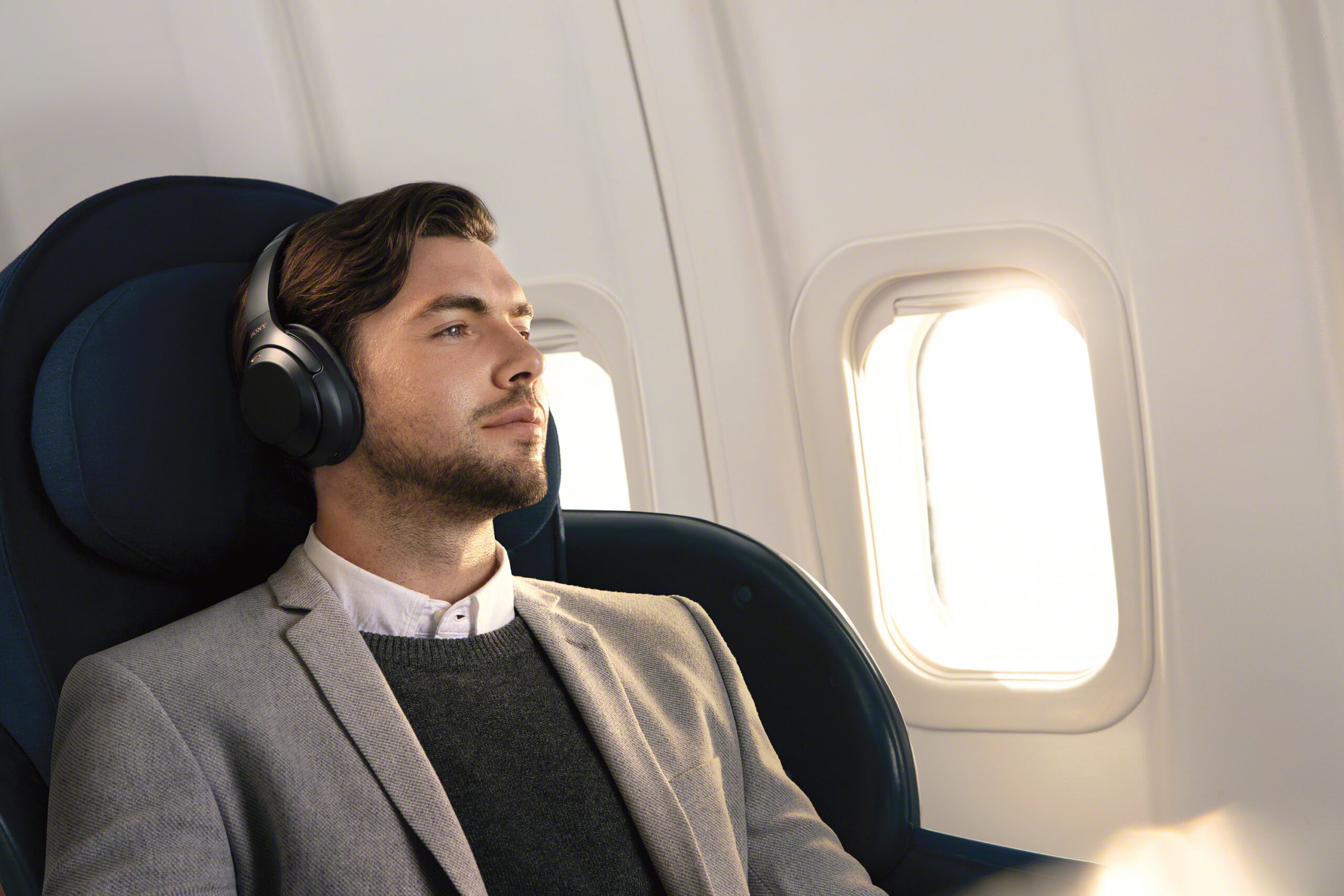 Sony press image of the Sony WH-1000XM3 active noise-cancelling headphones. A man is wearing them in a plane.