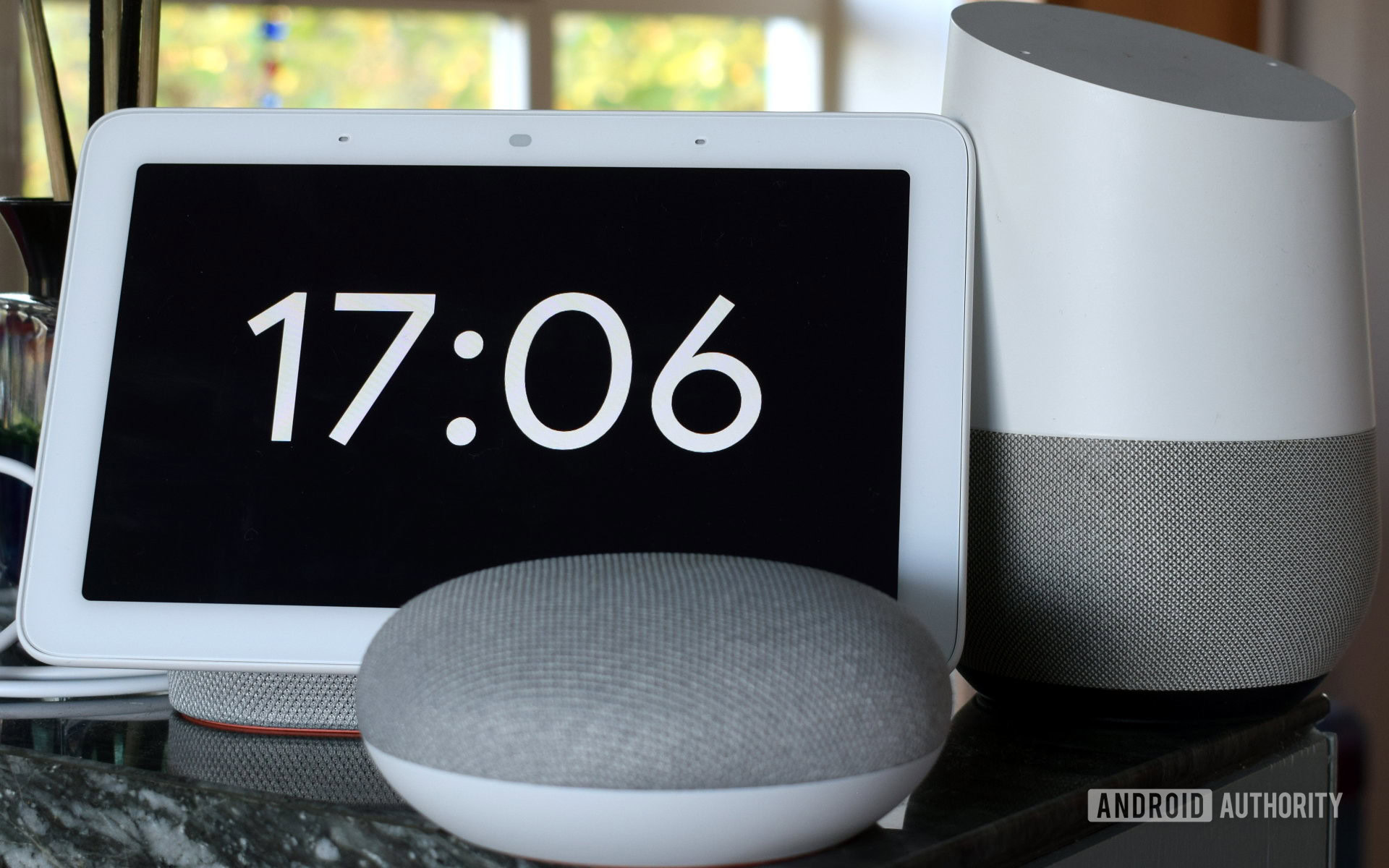 Photograph of Google Home Hub, Home Mini, and Home side by side