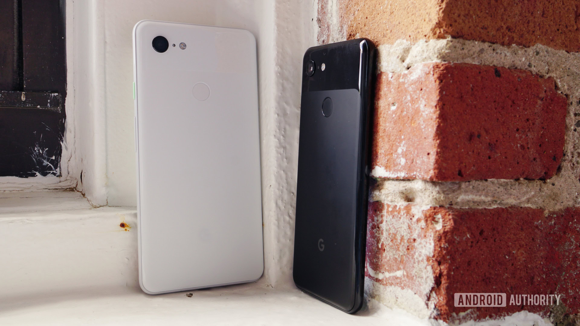 Google Pixel 3 and Pixel 3 XL stood upright outdoors against brickwork. 