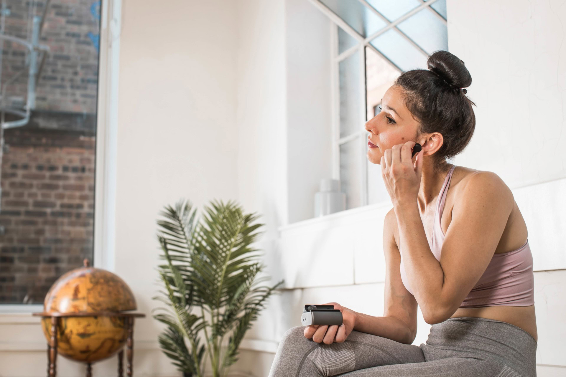 true wireless - RHA TrueConnect product image of an athletic woman inserting the left earbud into her ear.