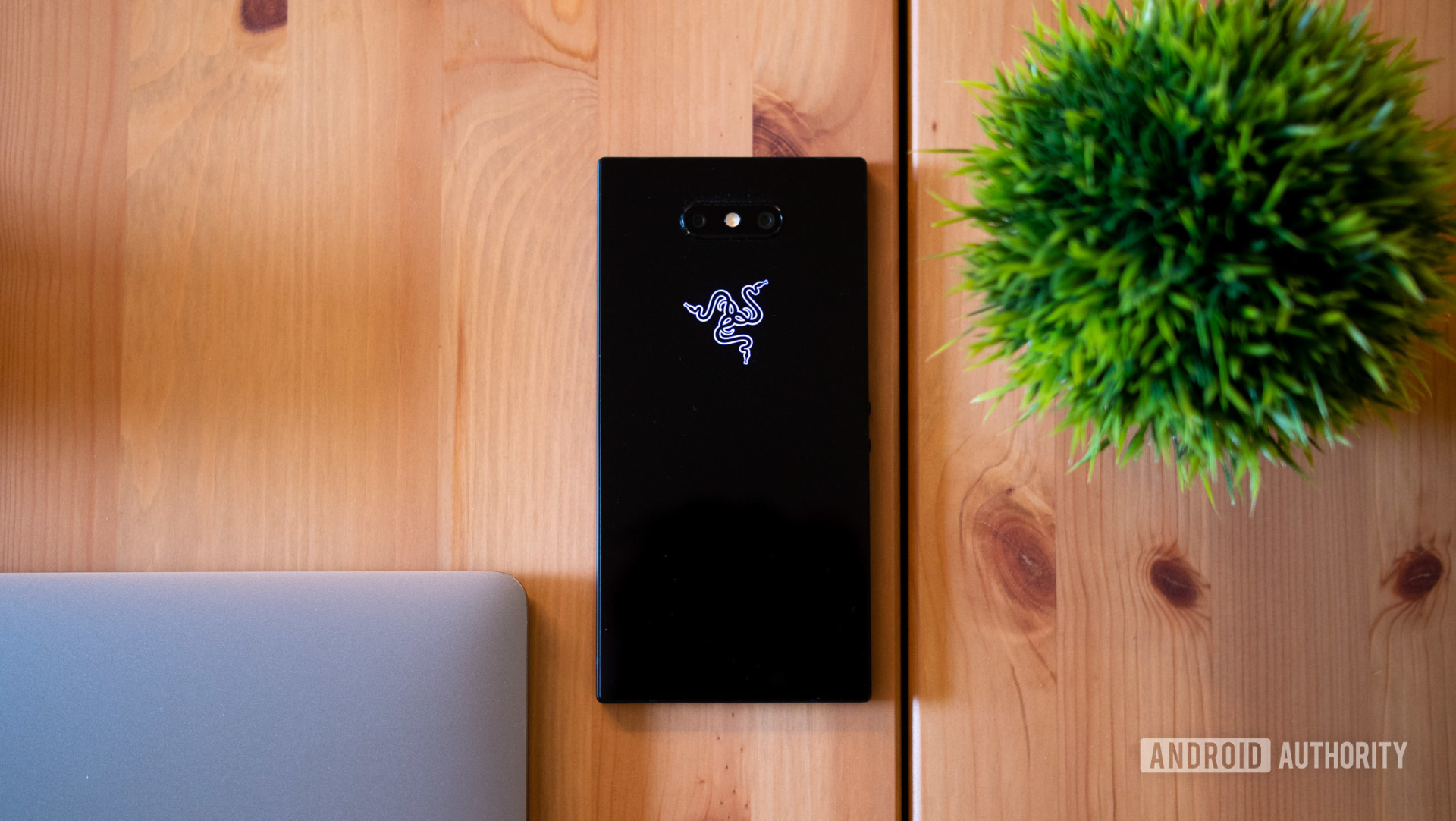 Back side view of the Razer Phone 2 laid on a wooden table.