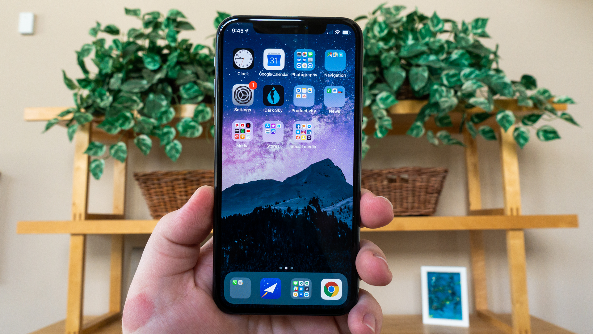 A hand holding an iPhone XS, showing off the display.