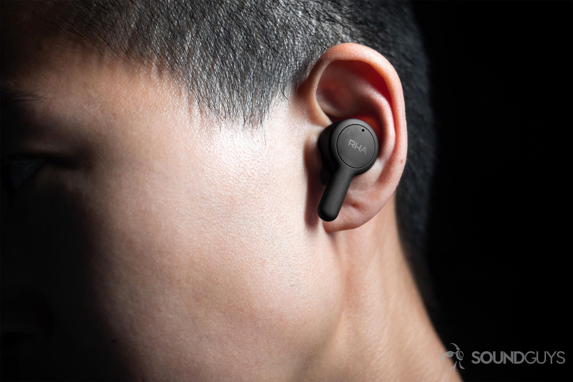 The left RHA TrueConnect earbud being worn by a woman, it protrudes a bit from the ear with the stem angled downward.