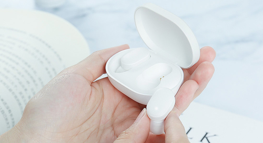 Xiaomi AirDots lifestyle product image of an earbud in the hand and the case in the other.