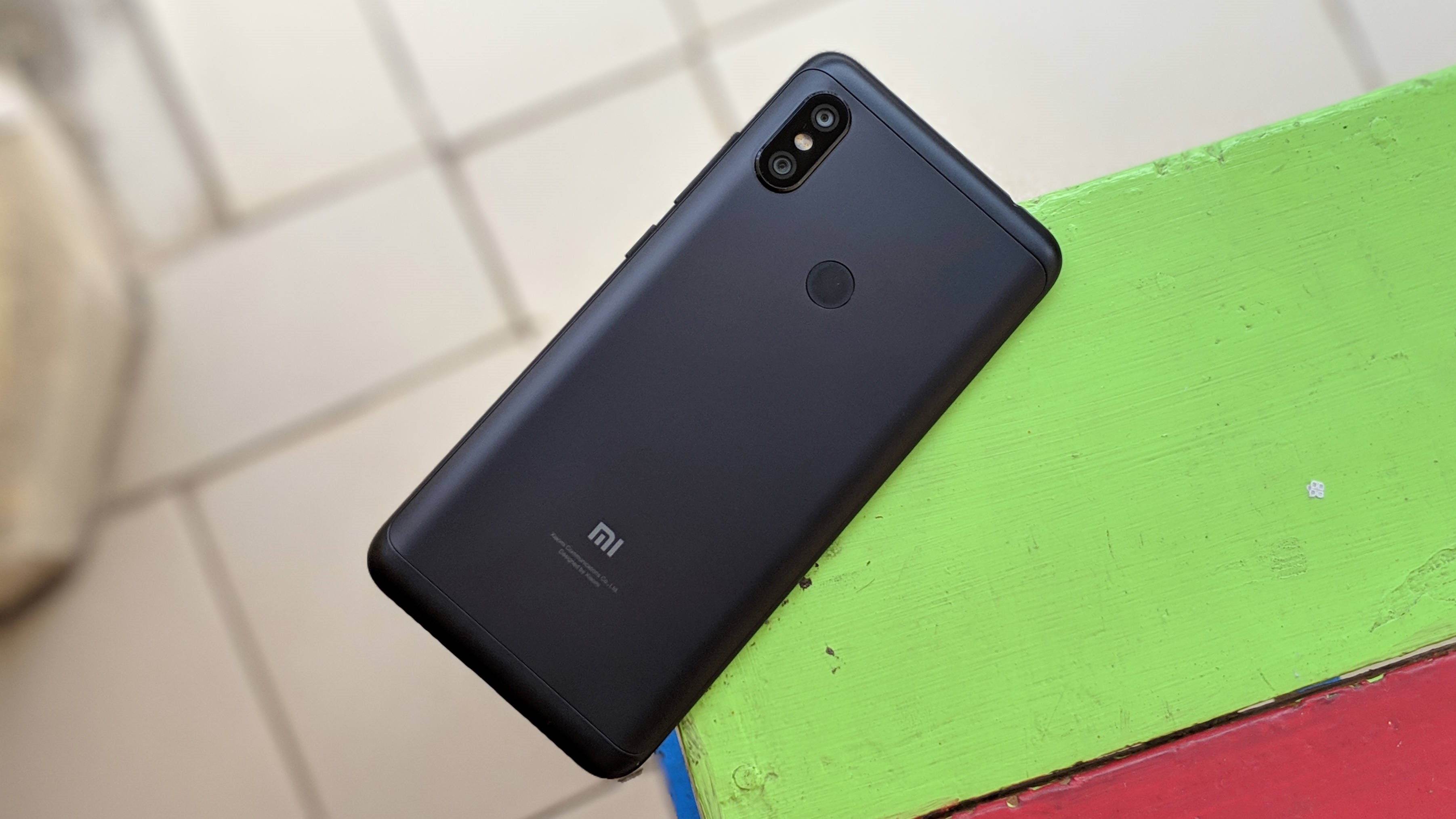 Photo of the backside of a black Redmi Note 6 Pro on a colorful table.
