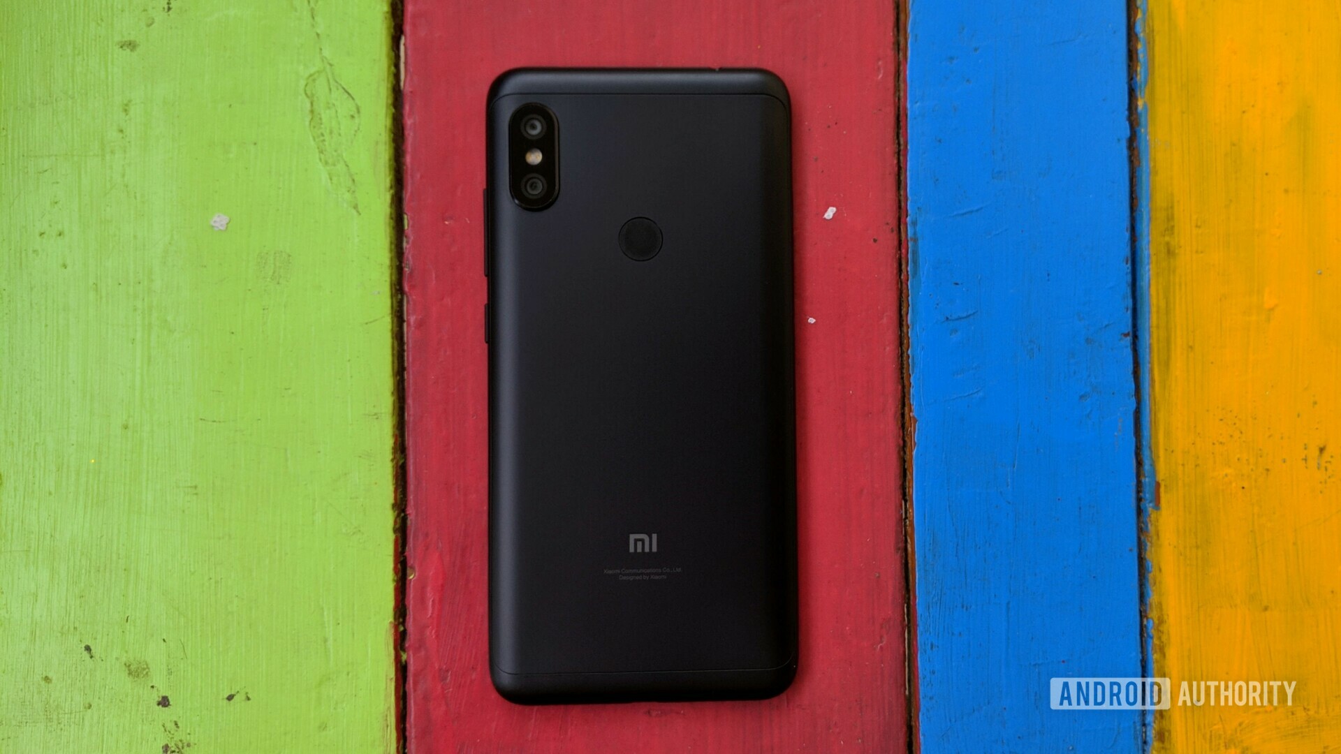 Photo of the backside of a Redmi Note 6 Pro on a colorful wooden background.