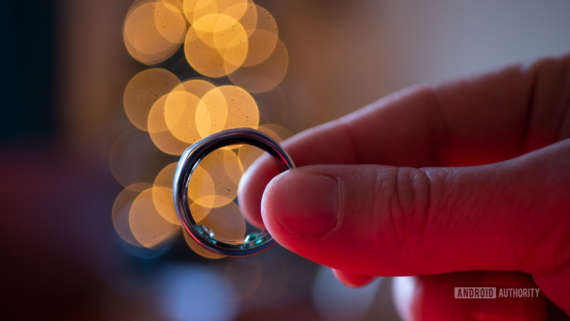 A user holds his Oura Ring 2 in front of a Christmas tree.
