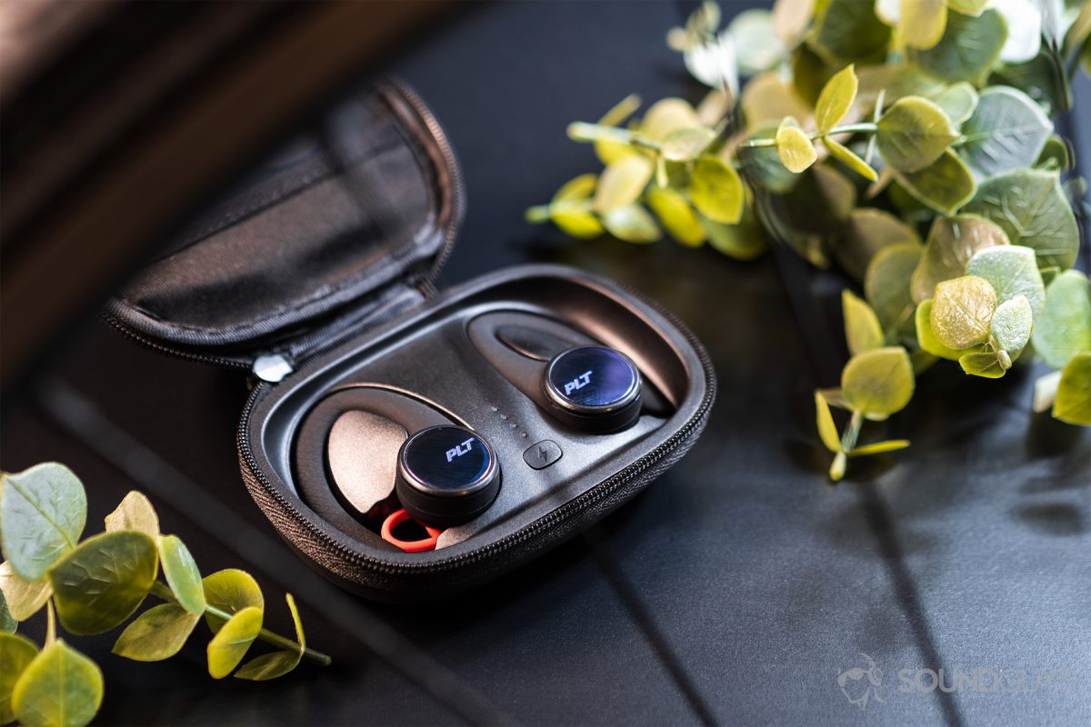 USB-C Headphones - Poly BackBeat Fit 3100: The earbuds in the case, which lays open, and flanked by two faux greenery pieces.