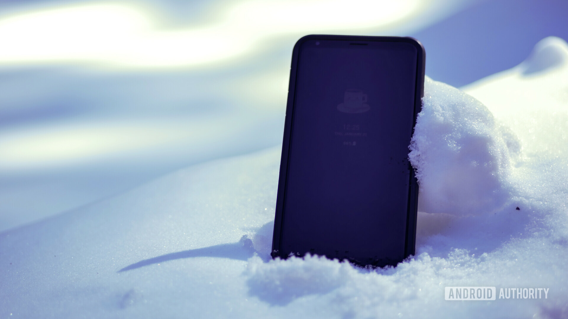 A cold phone half-buried in some white snow.