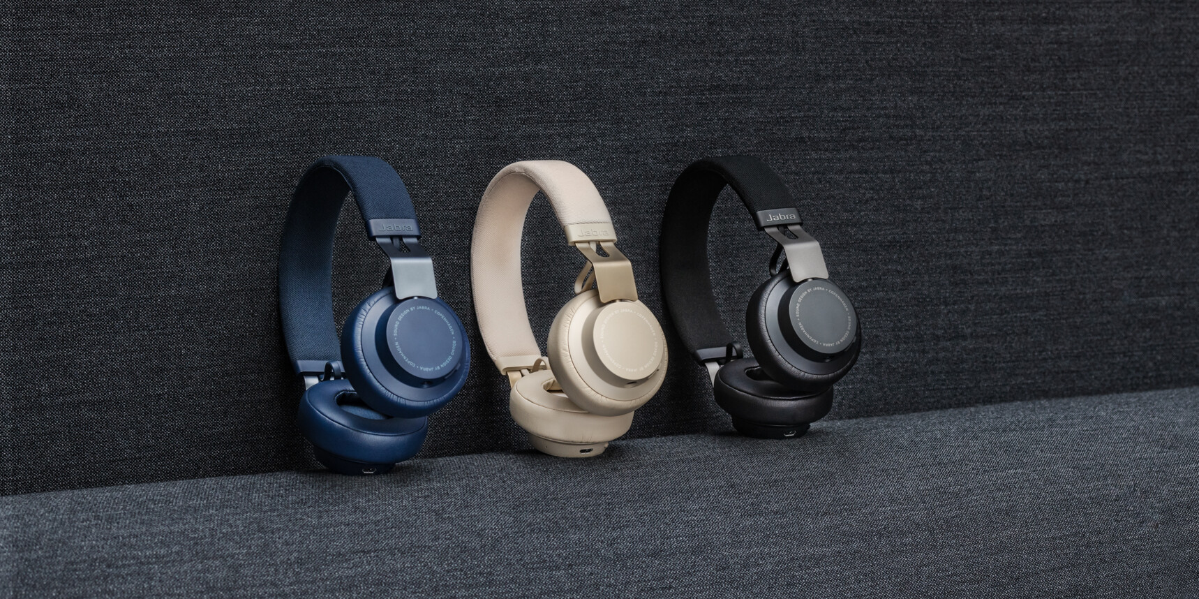 Jabra Elite 85h headphones (navy, beige, and black) against dark gray background.