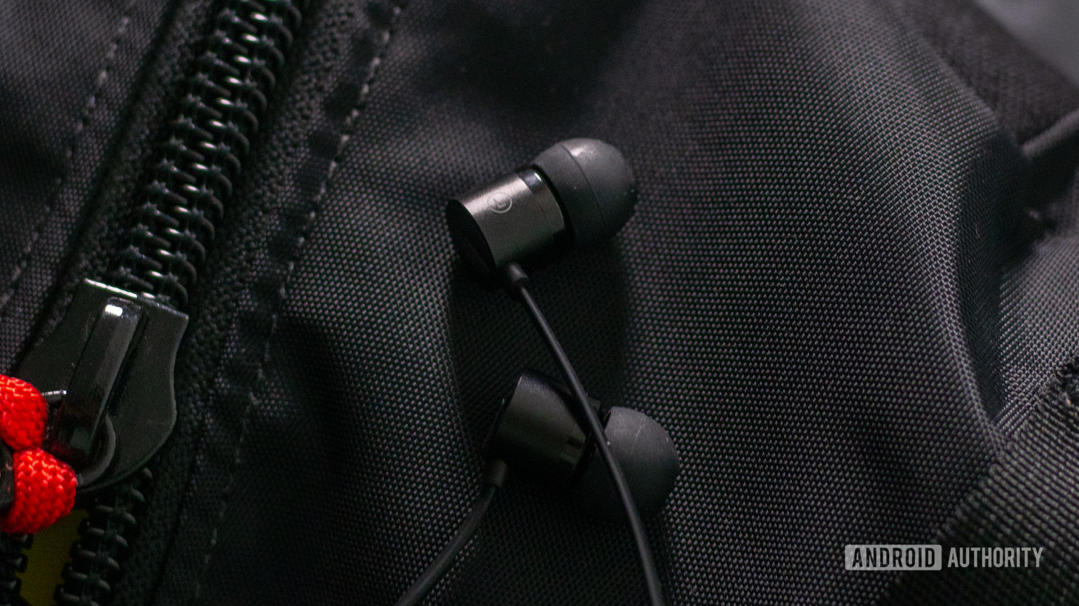 OnePlus Bullets USB-C headphones earbuds on black backpack. 