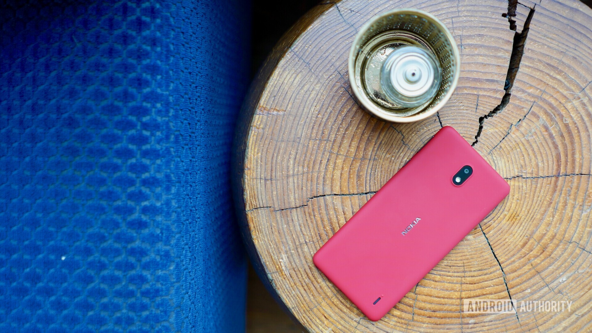 Backside photo of a pink Nokia 1 Plus laying on a tree log.