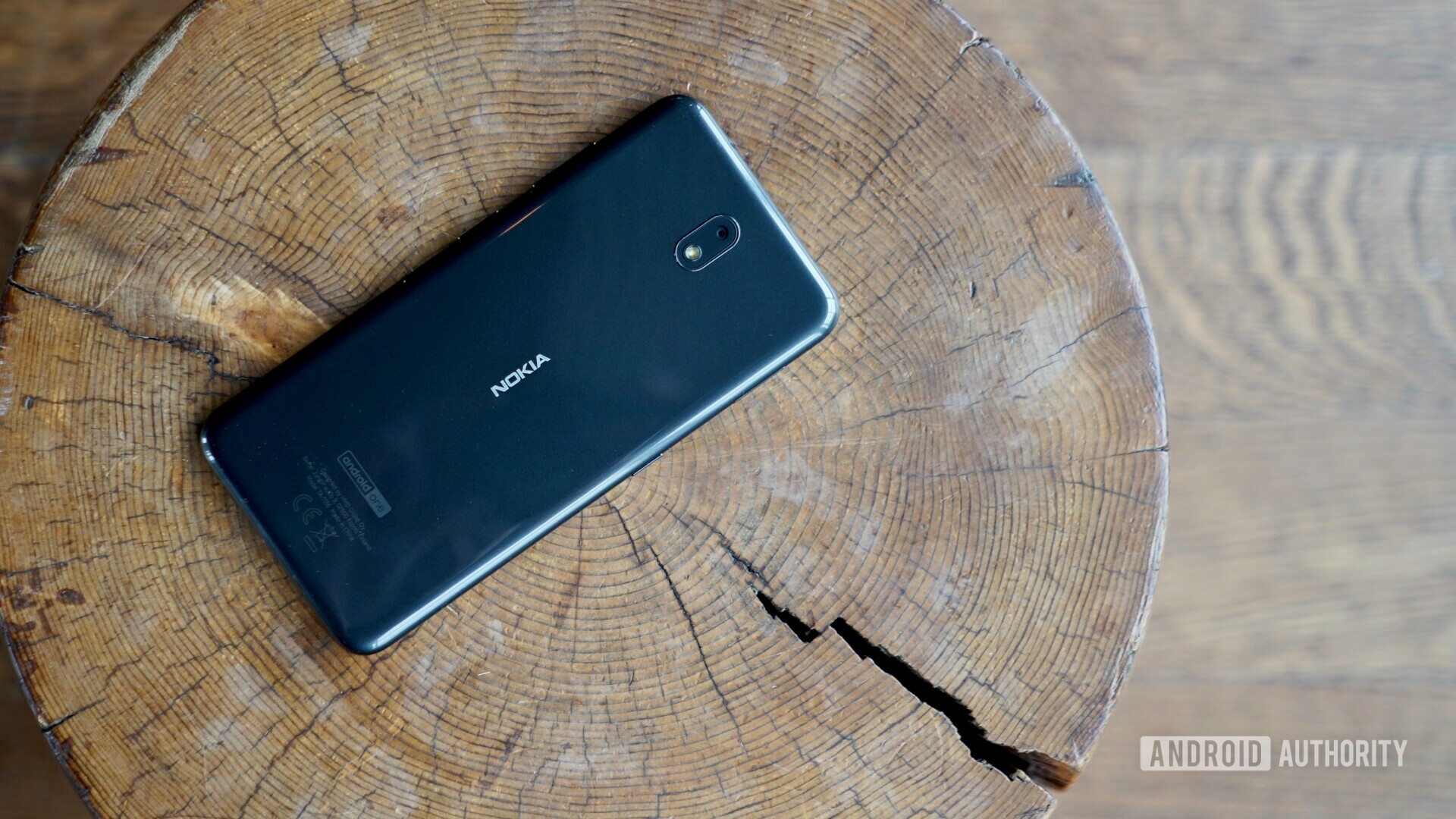 Backside photo of a black Nokia 4.2 laying on a tree log.