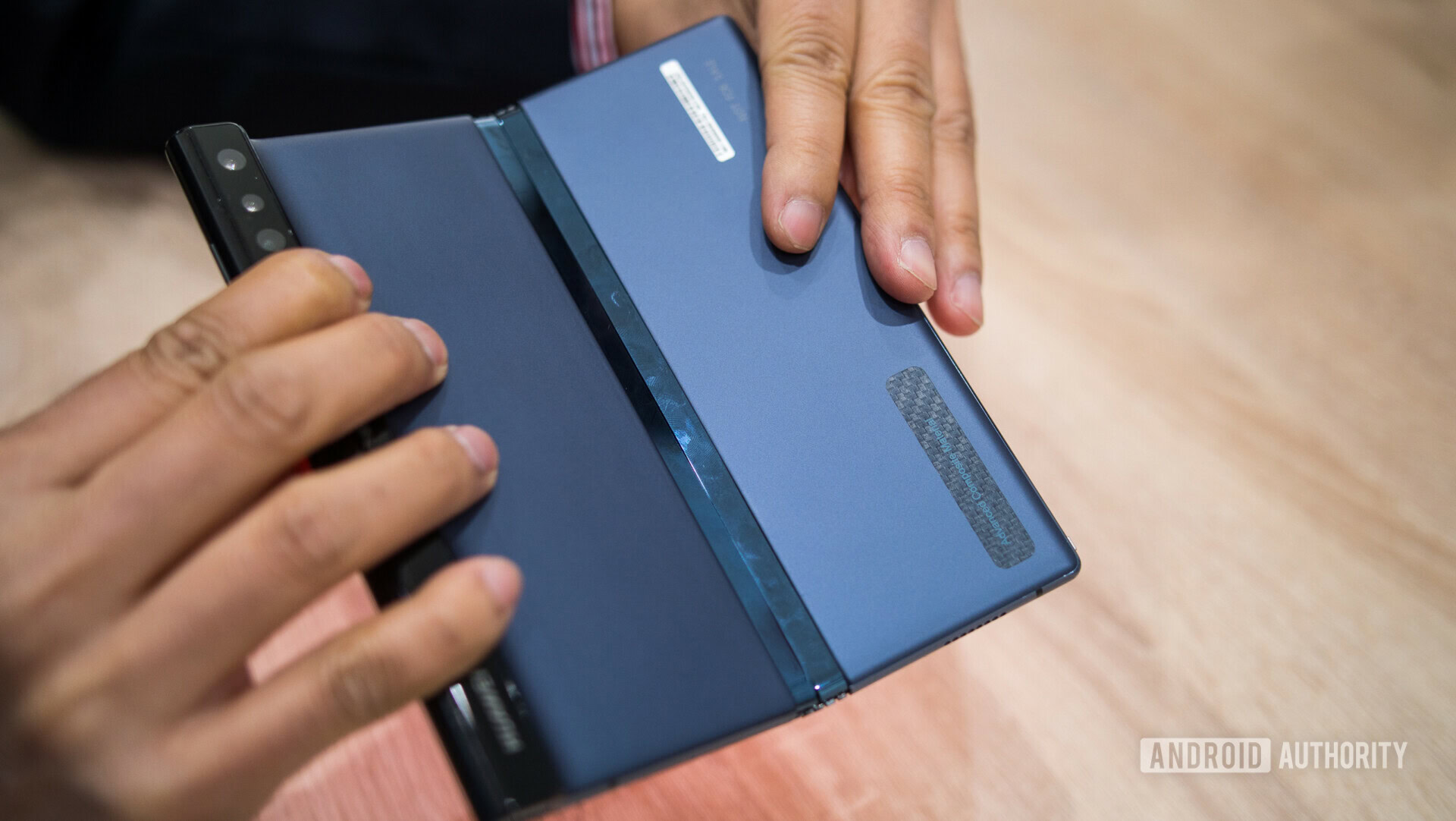 Backside photo of the HUAWEI Mate X Foldable Phone held in a hand at a MWC 2019 presentation.