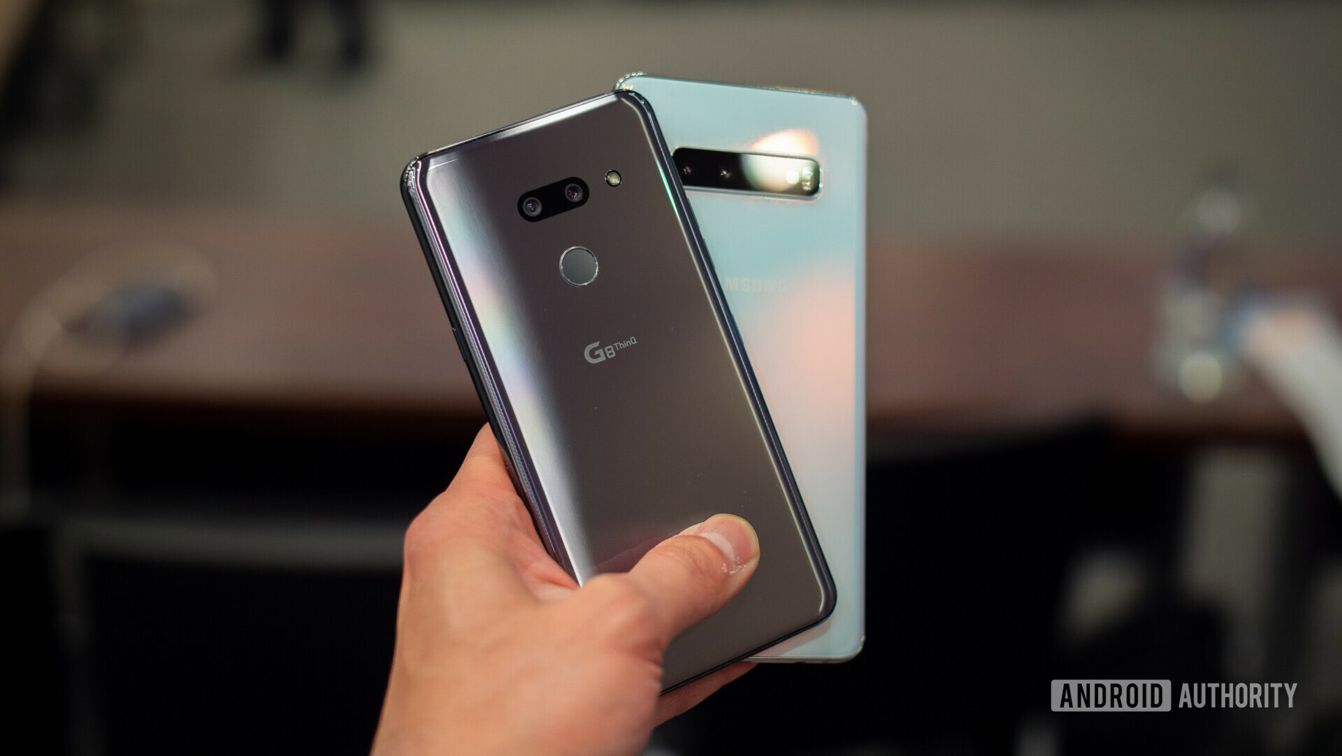 Backside photo of the LG G8 ThinQ and Samsung Galaxy S10 held in a hand