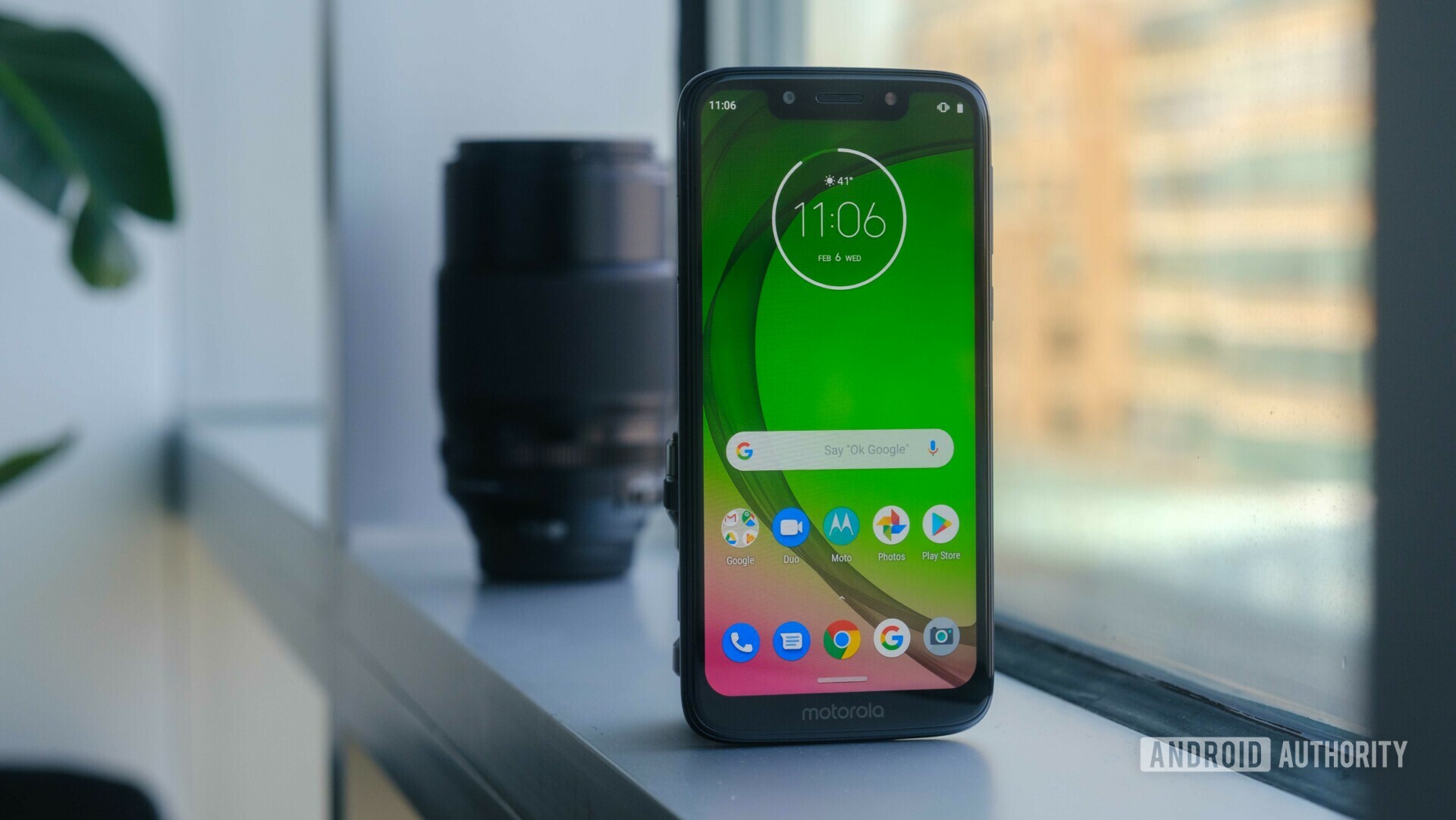 Frontside of the new Motorola Moto G7 Play standing in a upright position next to a window.
