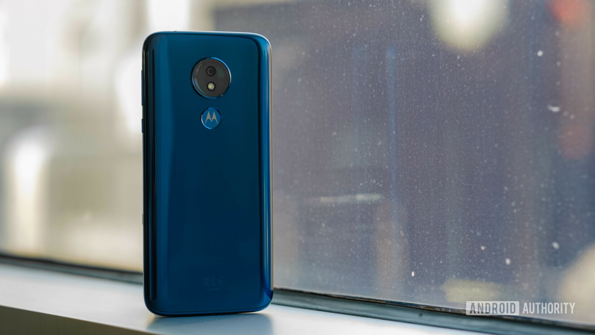 Backside of the new Motorola Moto G7 Power in dark blue color standing upright in front of a window.