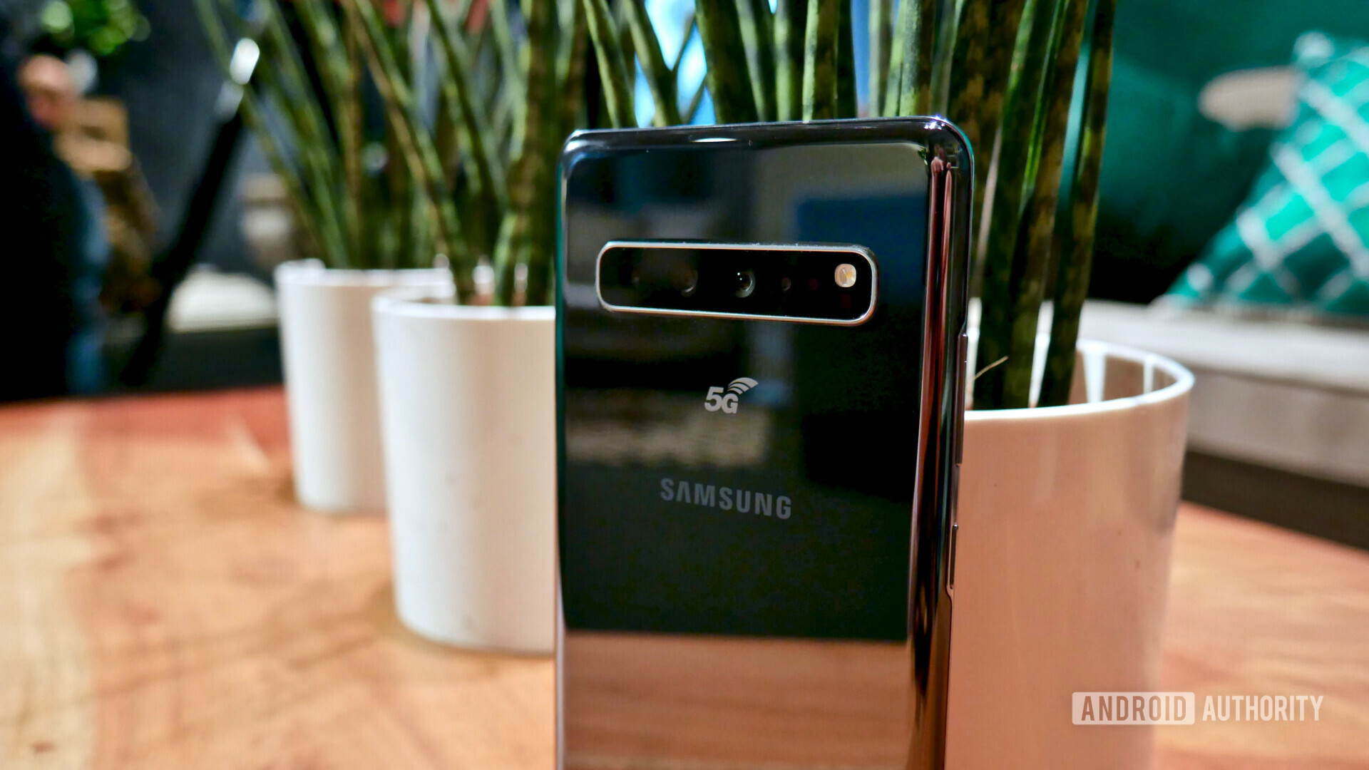 Backside photo of the Samsung Galaxy S10 5G focusing on the tripple cameras with plants in the background.