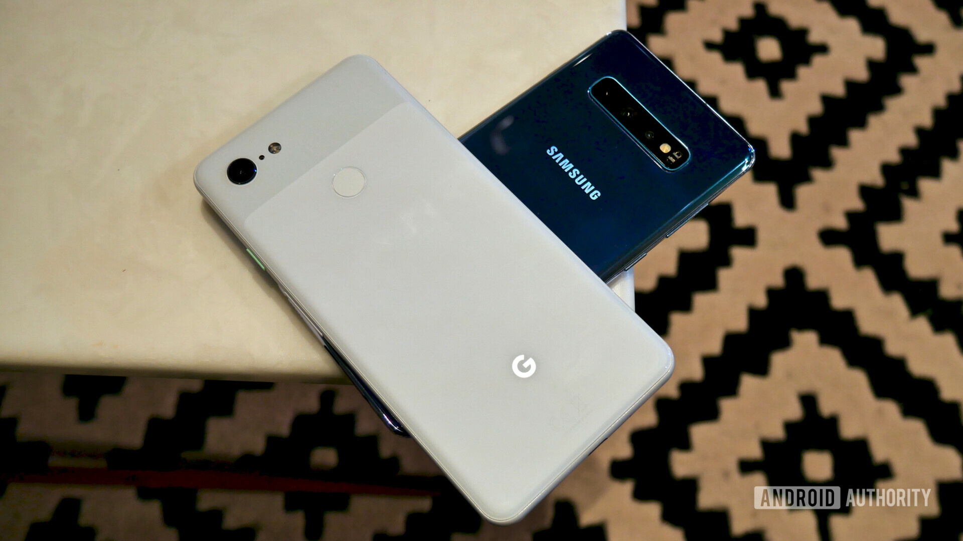 Backside photo of the Samsung Galaxy S10 Plus next to a Google Pixel 3 XL on a white table.