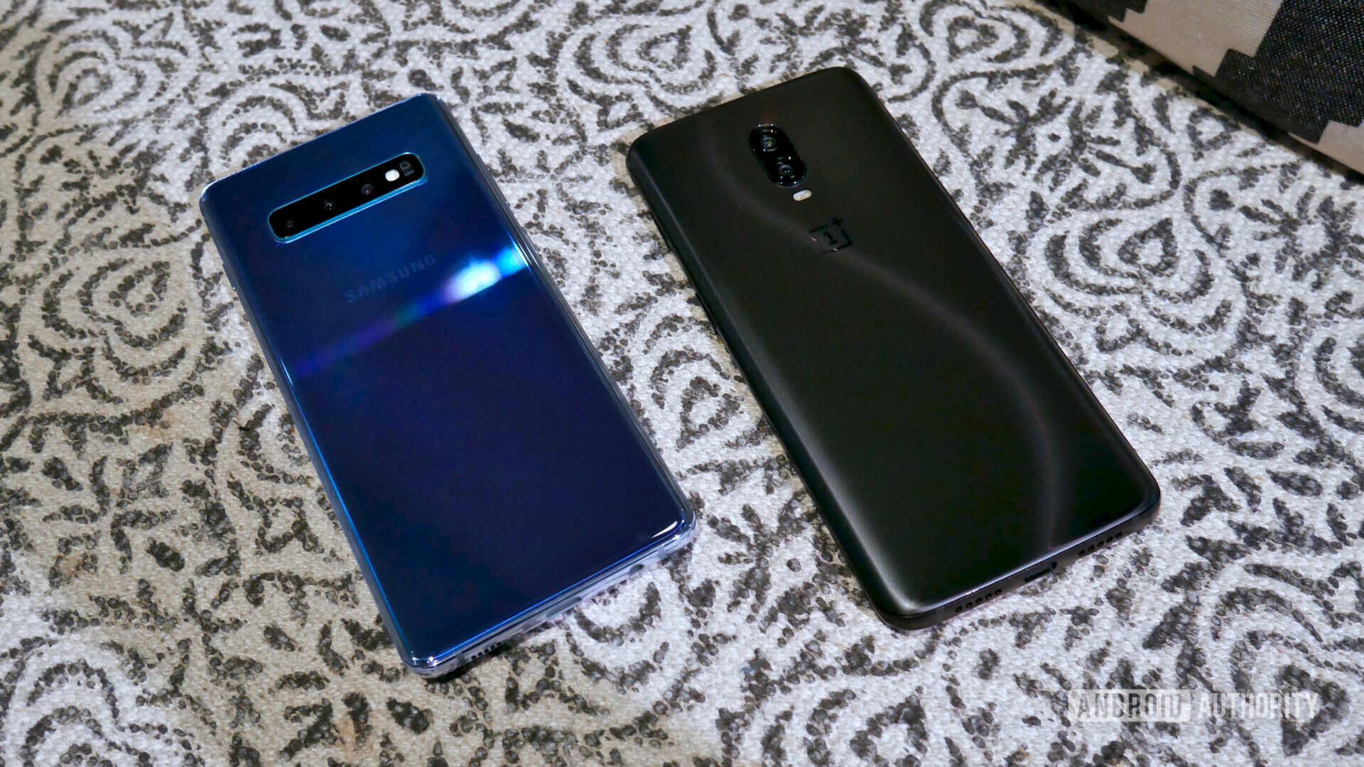 Backside of the Samsung Galaxy S10 next to an OnePlus 6T laid on a table.