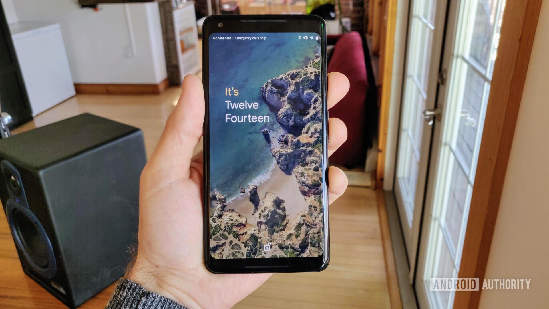 A hand holding a Google Pixel 2 XL running Android Q beta with the customized Android Q Lock Screen.