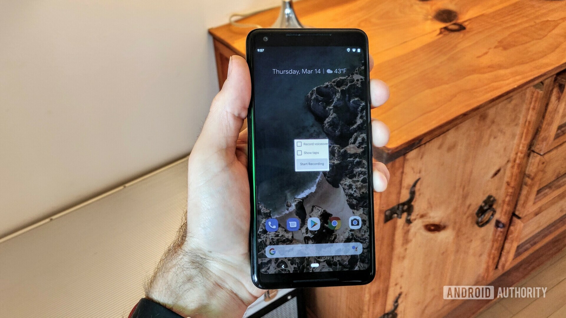 A photograph of a hand holding a Google Pixel 2 XL with the new Android Q screen recorder on the display.