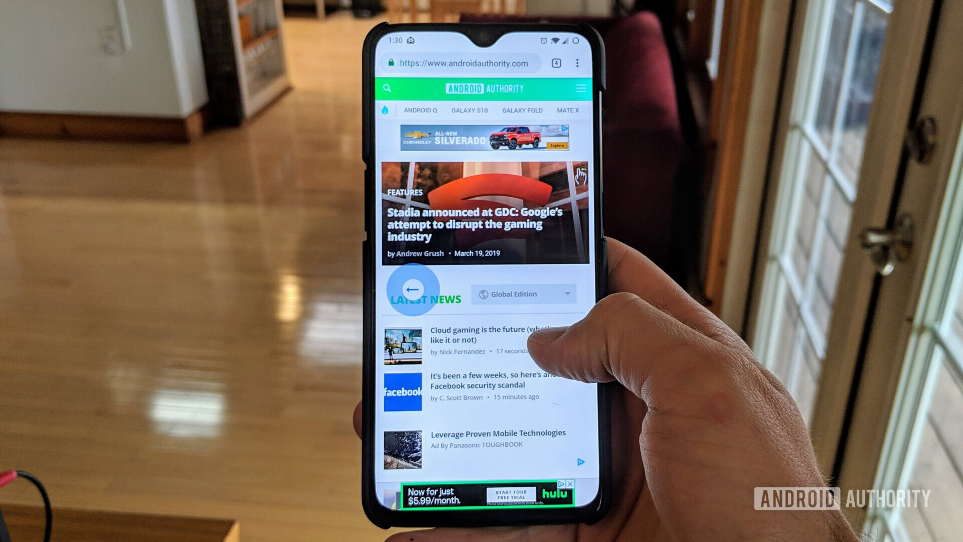 A photograph of a hand holding a smartphone demonstrating the new Chrome gestures for navigating through web pages.