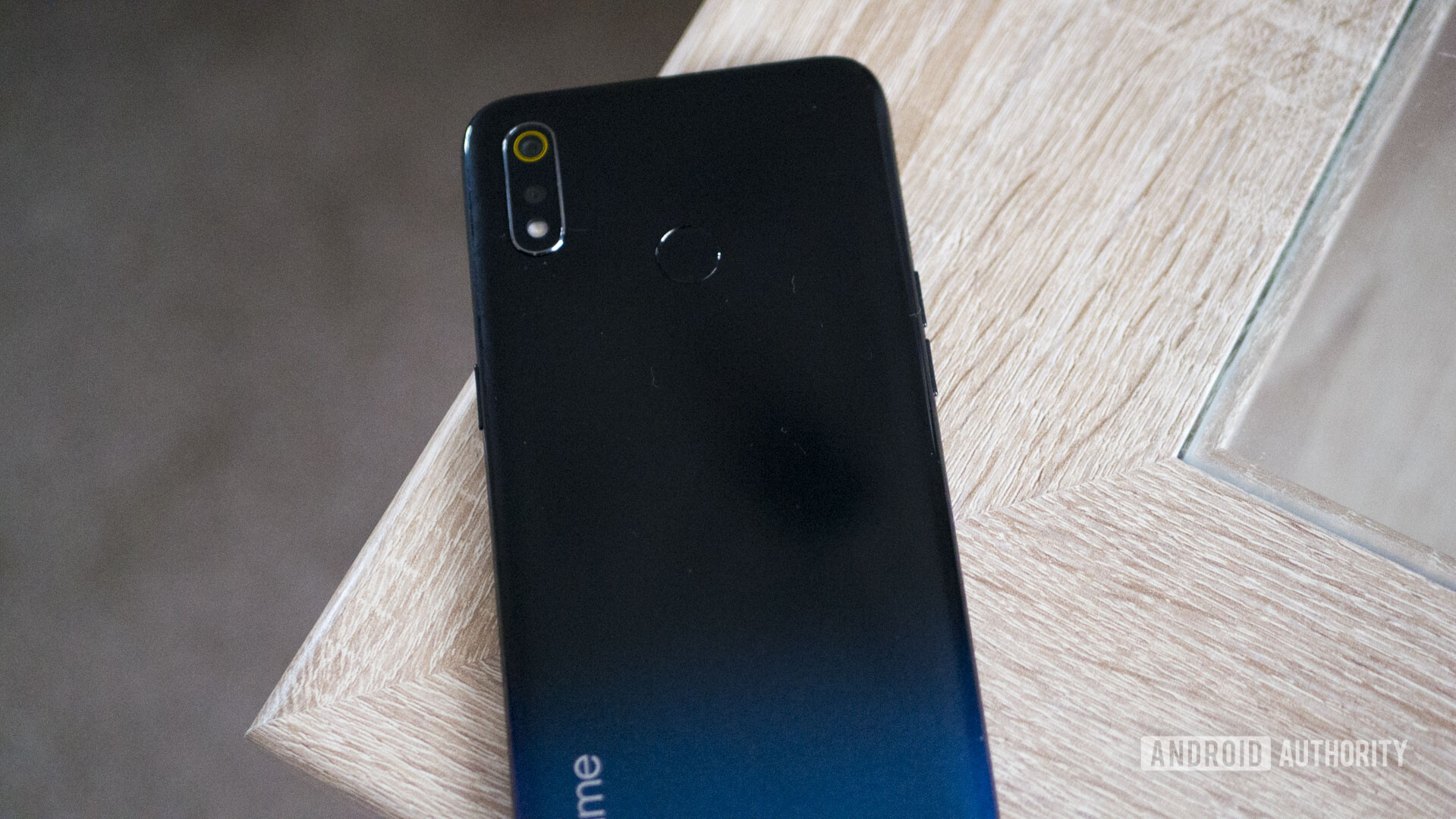 Backside of a black Realme 3 laid on a table.