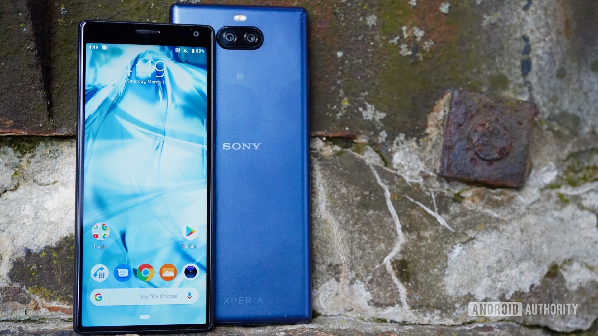 Front side of the Sony Xperia 10 with a display turned on next to a Xperia 10 Plus against a old concrete wall.